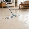 Floor squeegee removing water from ceramic tile flooring in a living room.