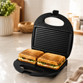Sandwich maker with dual cooking plates for preparing toasted sandwiches for breakfast, snacks, and light meals.